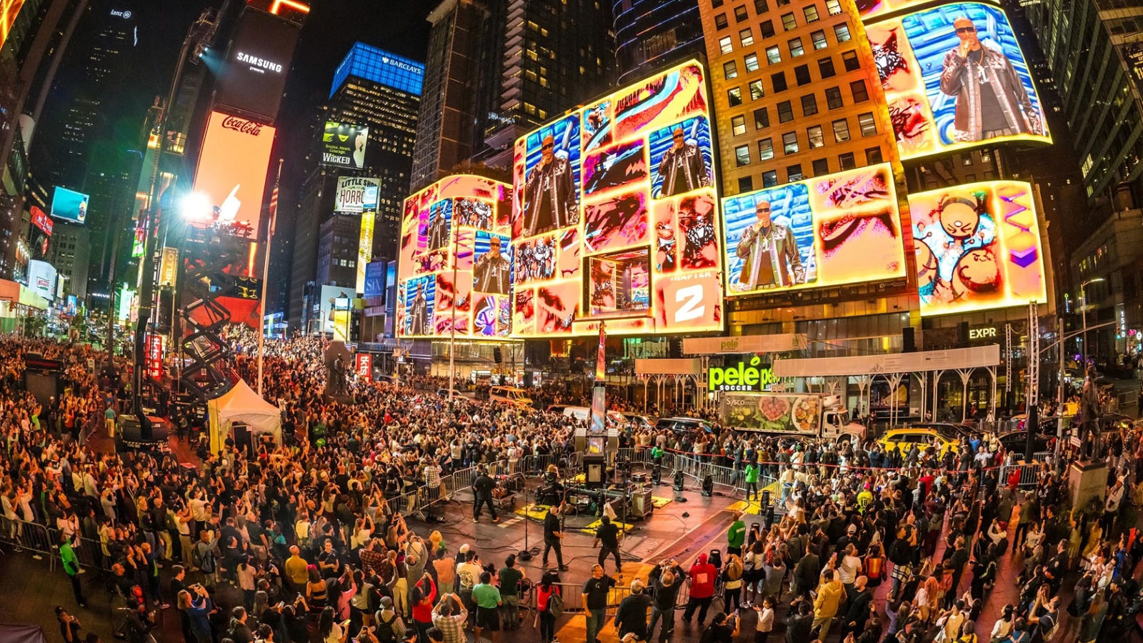 Ultra festival crowd in Times Square below towering LED screens of a performer