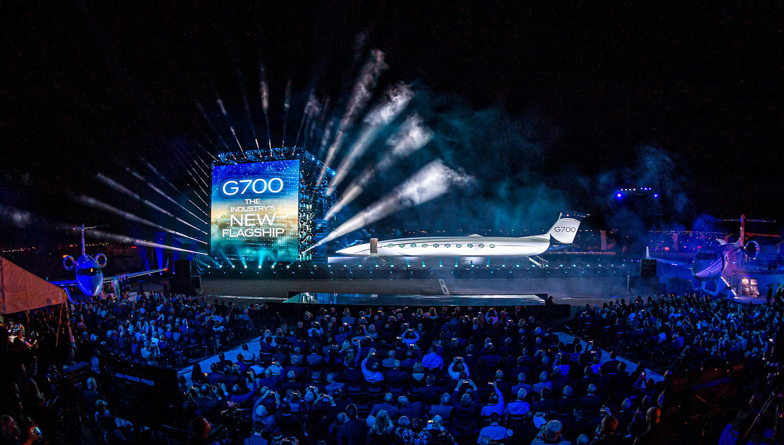 Gulfstream G700 jet unveiled on stage with pyrotechnics before a large seated crowd at a launch