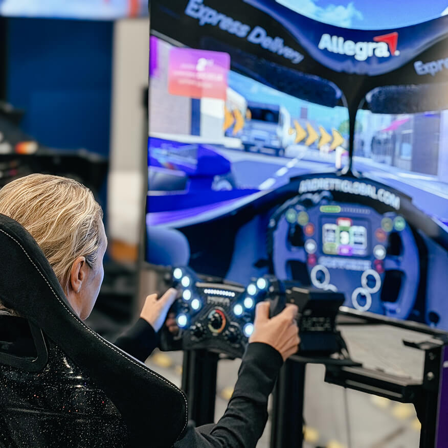 Guest racing an Allegra-branded F1 driving simulator at a brand activation