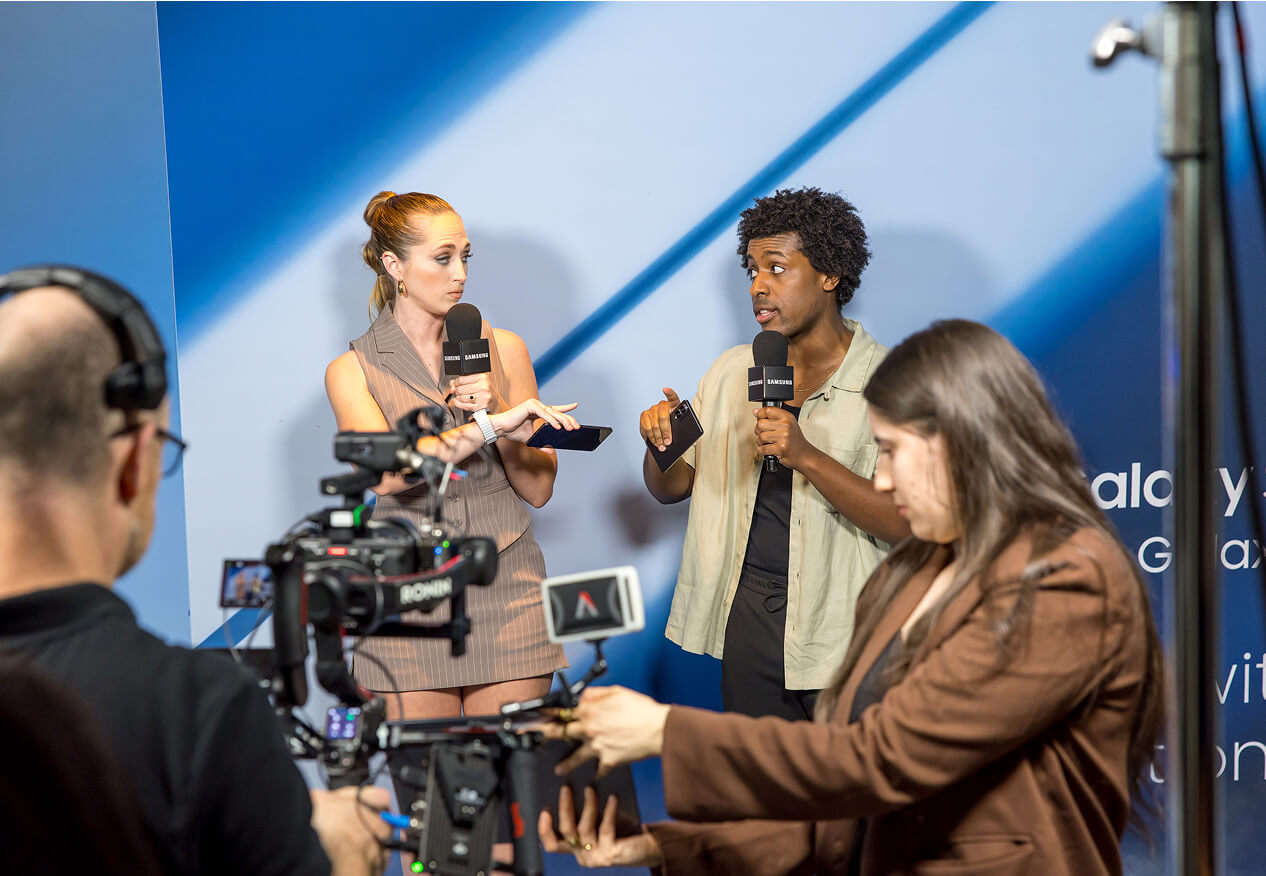 Two presenters interviewed on camera against a blue Samsung Galaxy backdrop
