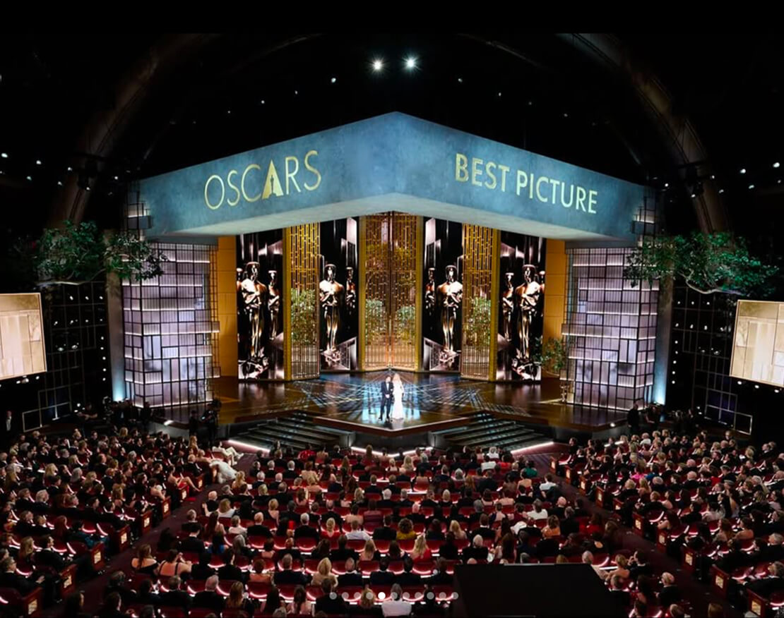 Oscars Best Picture stage set with towering Academy Award statues and full seated audience