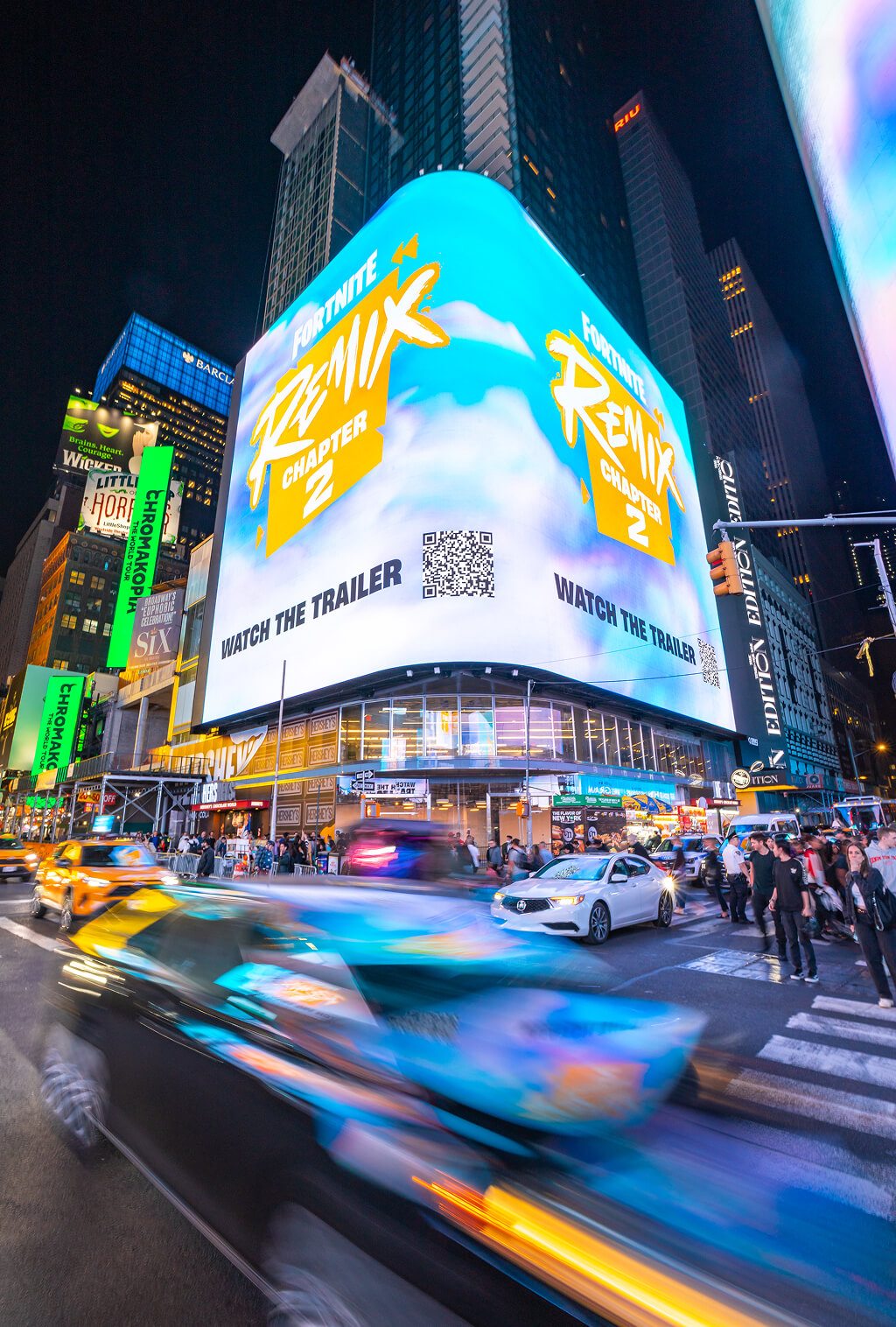 Times Square billboard advertising Fortnite Chapter 2 Remix with light-trailed traffic below at night