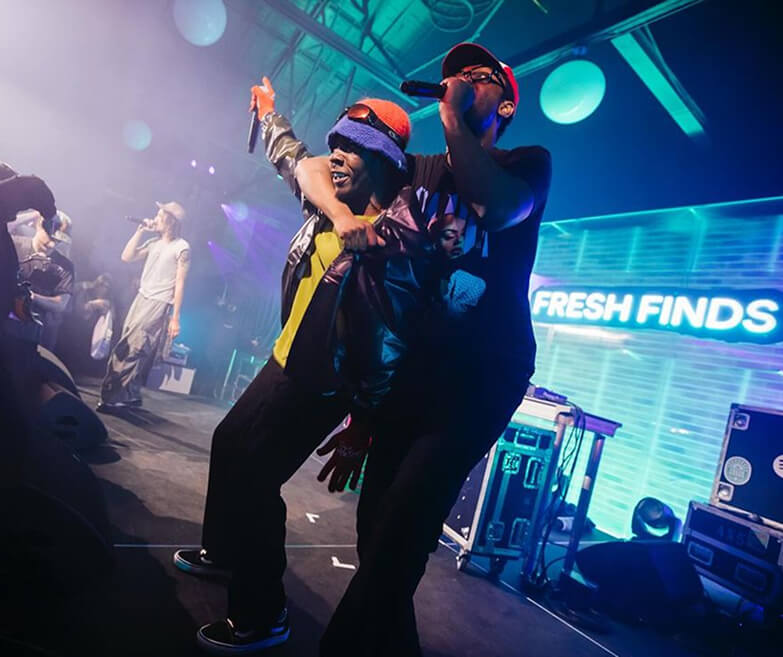 Two rappers perform energetically onstage beside Fresh Finds LED screen at Spotify event