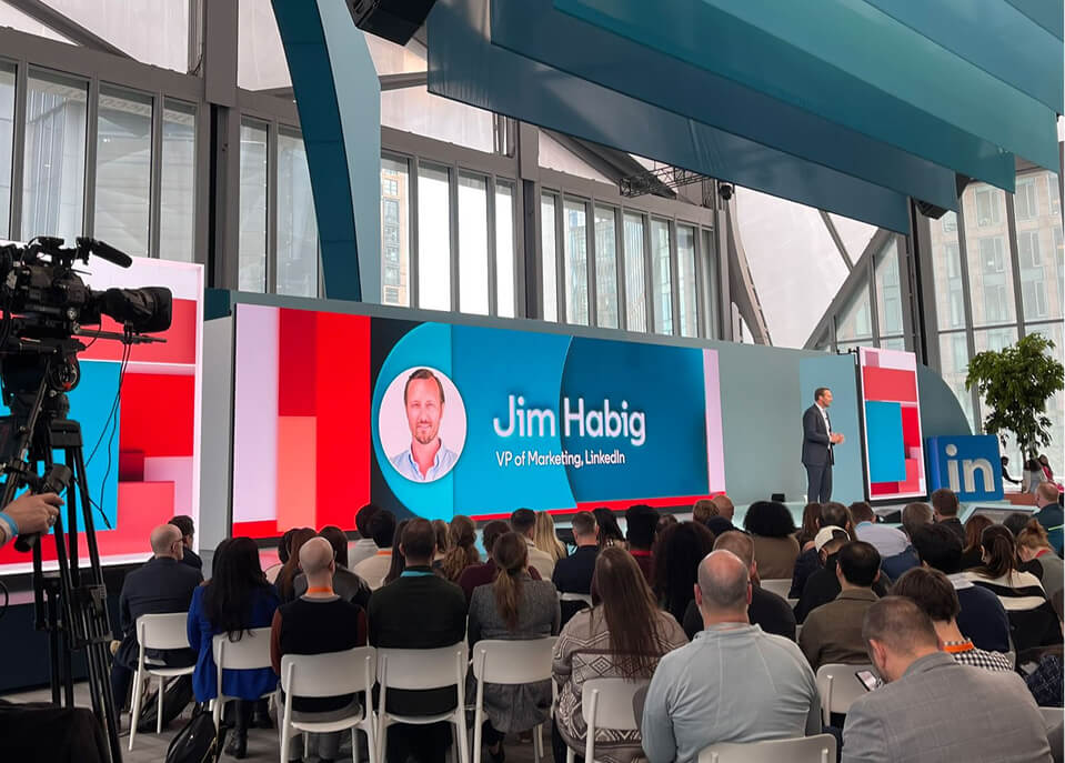 LED wall showing Jim Habig, VP of Marketing, addressing seated audience at LinkedIn B2Believe