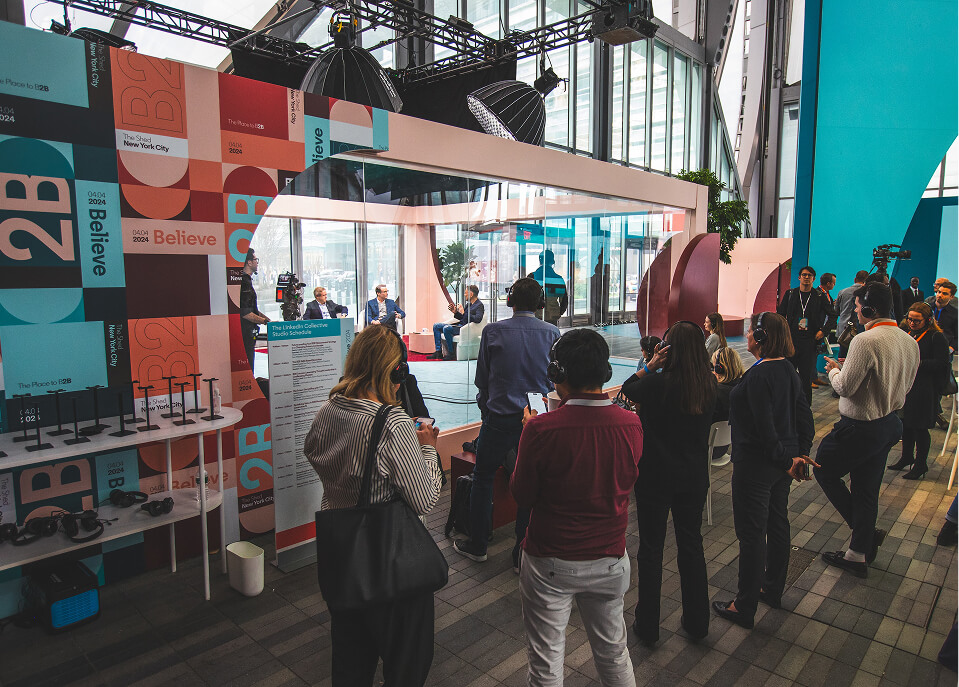 Guests in headphones watching a glass studio interview at the LinkedIn B2Believe activation