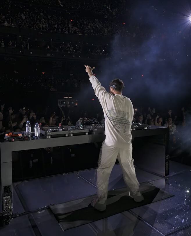 John Summit facing the arena crowd from the DJ booth, arm raised, at The Sphere