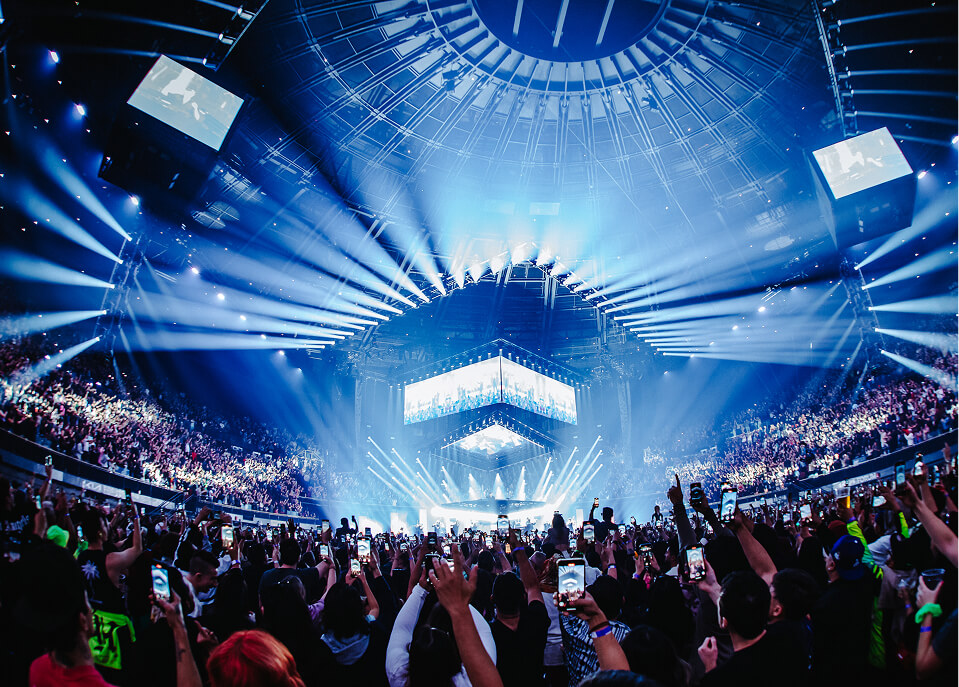 Phones raised across a huge crowd under blue beams at John Summit's arena show