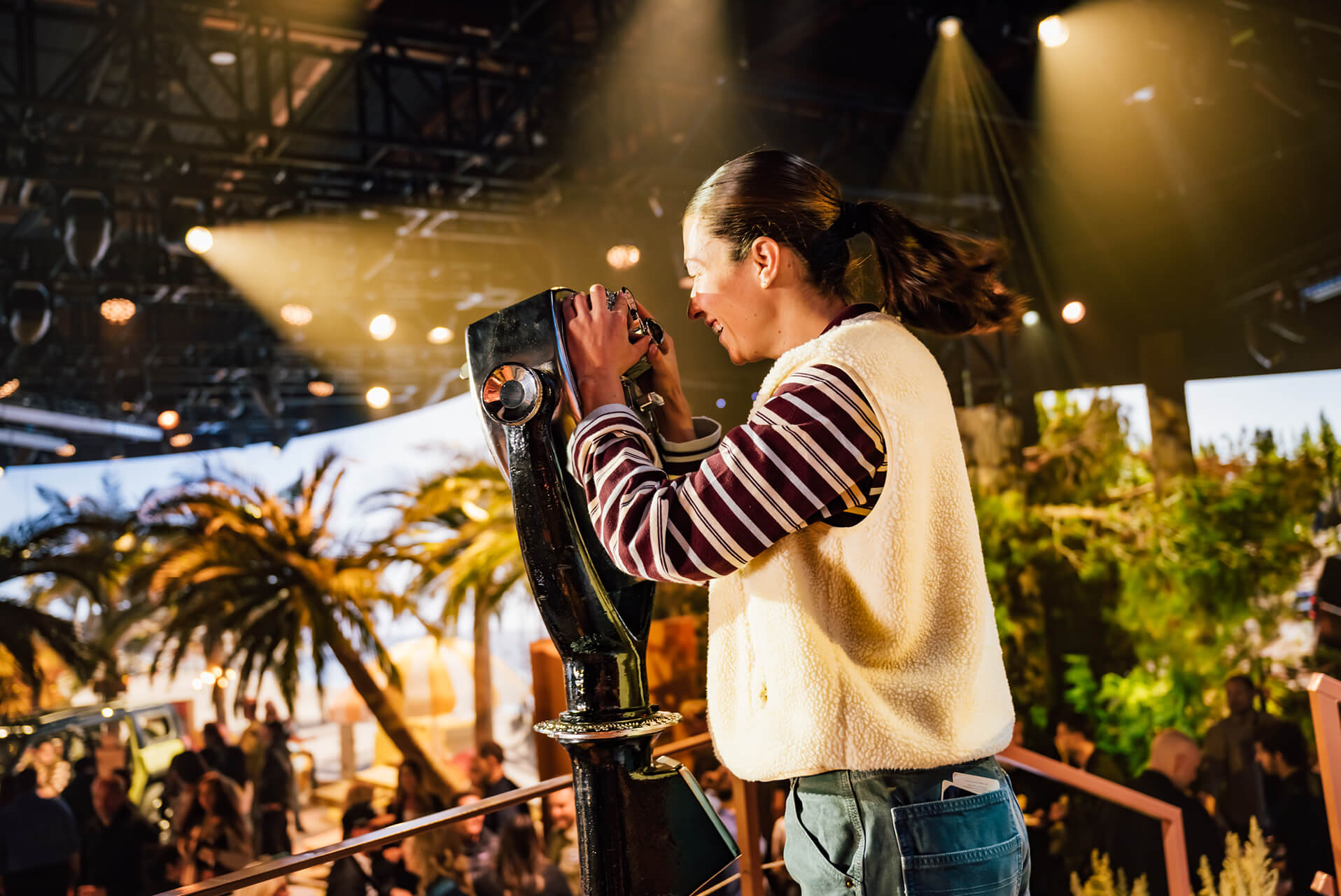 Smiling guest looks through a viewer over a palm-tree scene at the Jeep Recon reveal