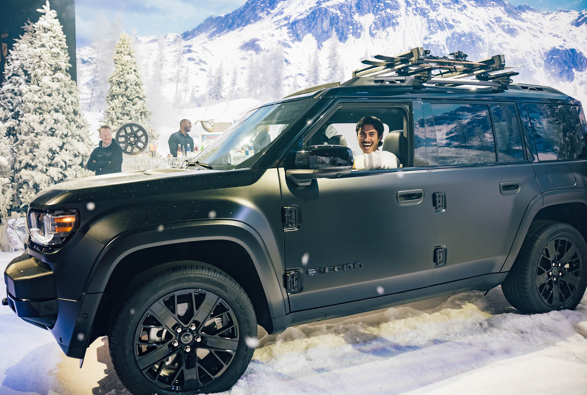 Guest laughs inside a black Jeep Recon in a snowy alpine set at the reveal event