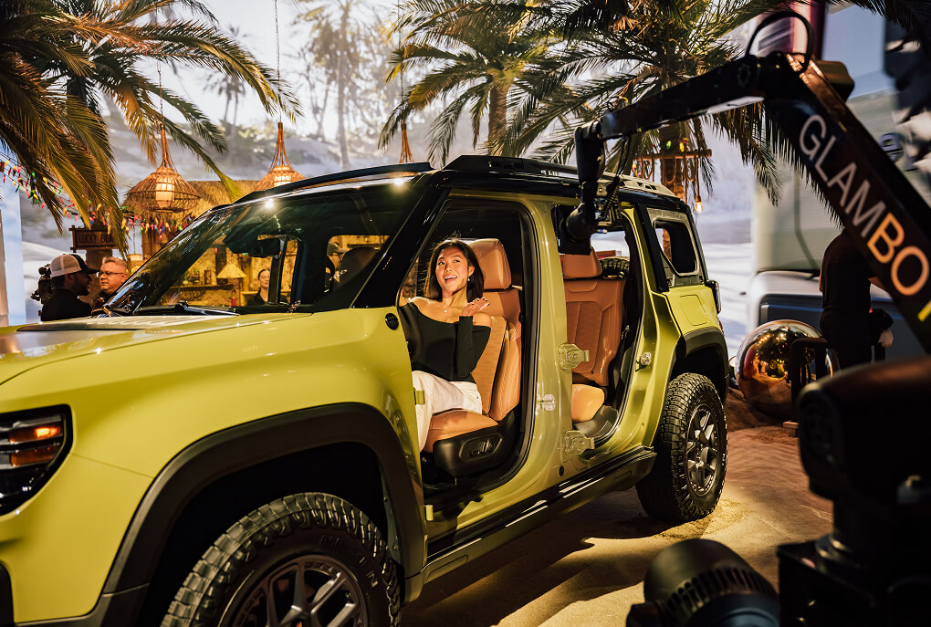 Woman poses in a lime-green Jeep Recon by a Glambot camera at the reveal event