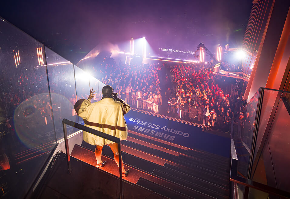 Performer descending stairs toward a packed crowd at the Samsung Galaxy S25 Edge rooftop launch