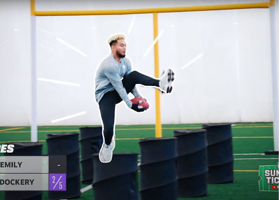 NFL Ultimate Fantasy Draft player leaping over barrels through an obstacle course challenge