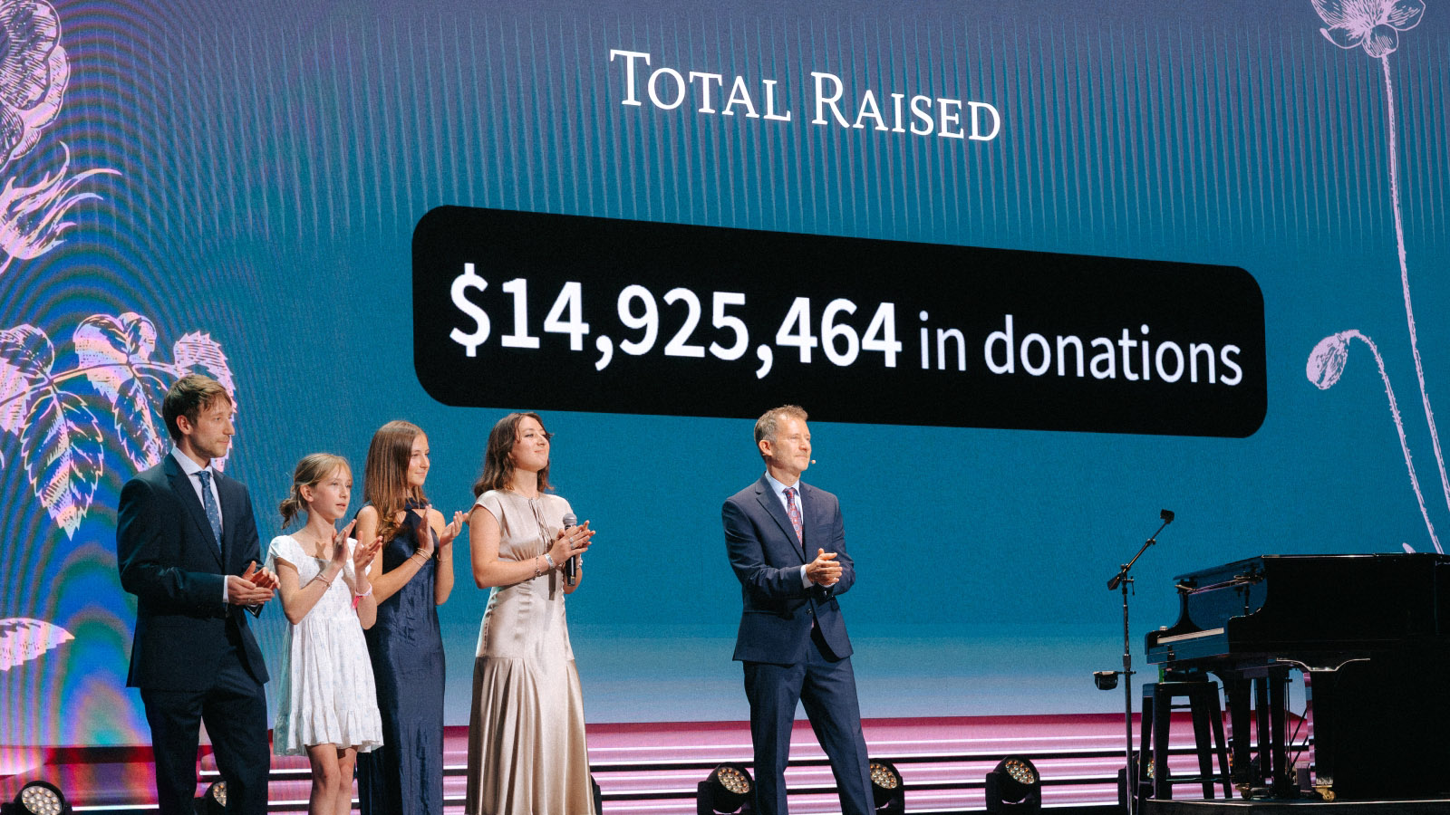 Susan's family on stage announcing $14.9M raised at Evening of Impact gala
