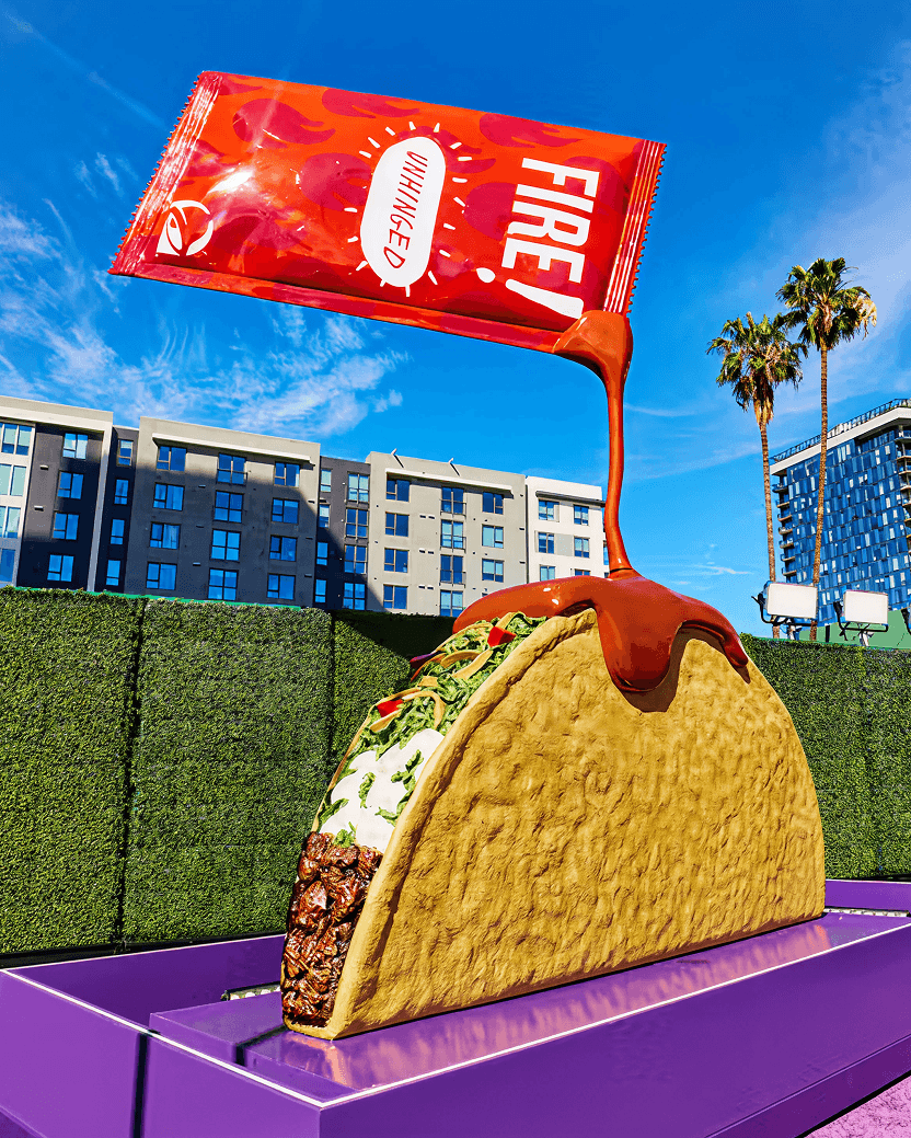 Guest posing beside a giant taco sculpture at an experiential brand activation