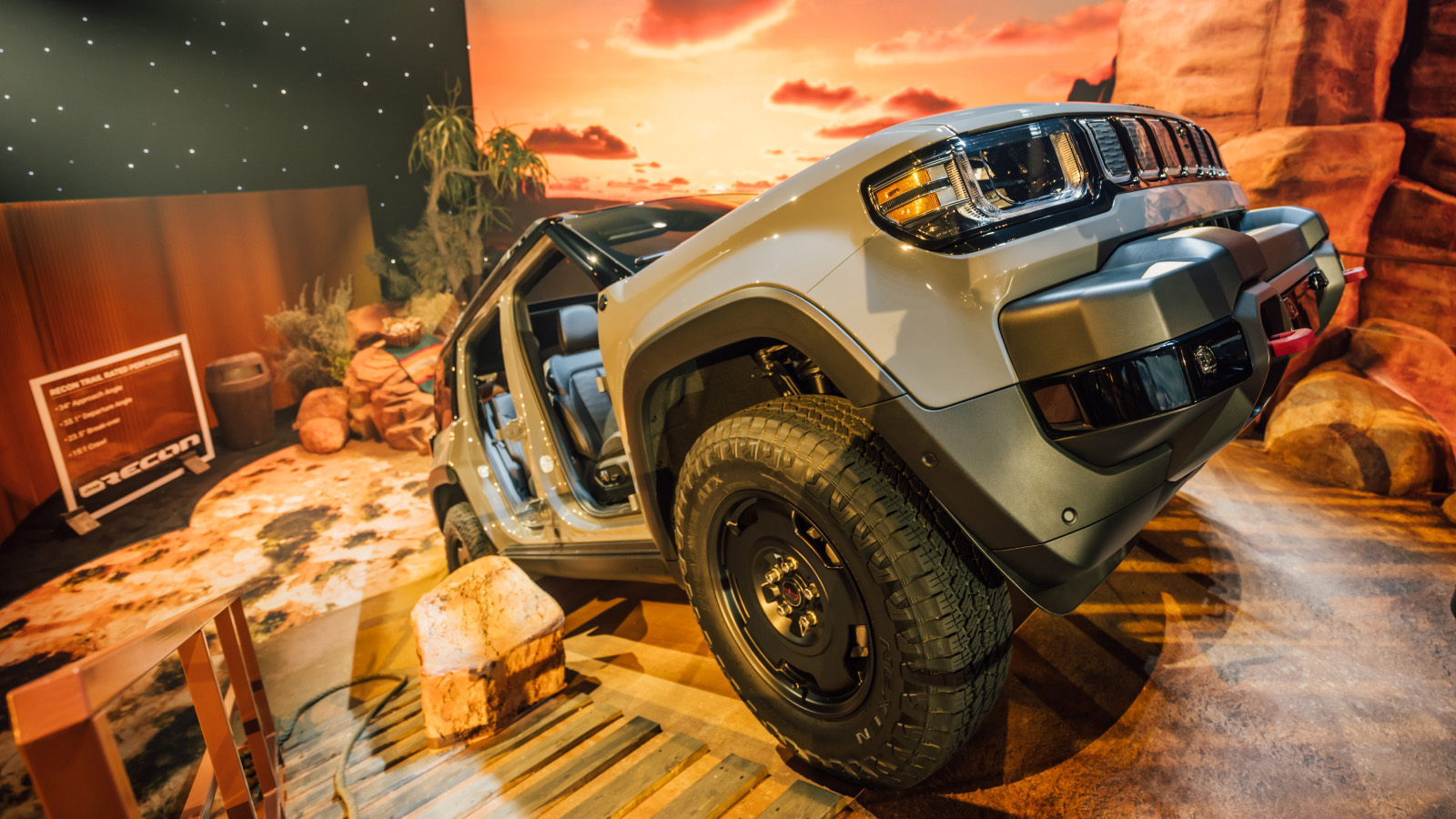 Jeep Recon SUV displayed on rocky terrain set with off-road stats sign in a desert sunset diorama.